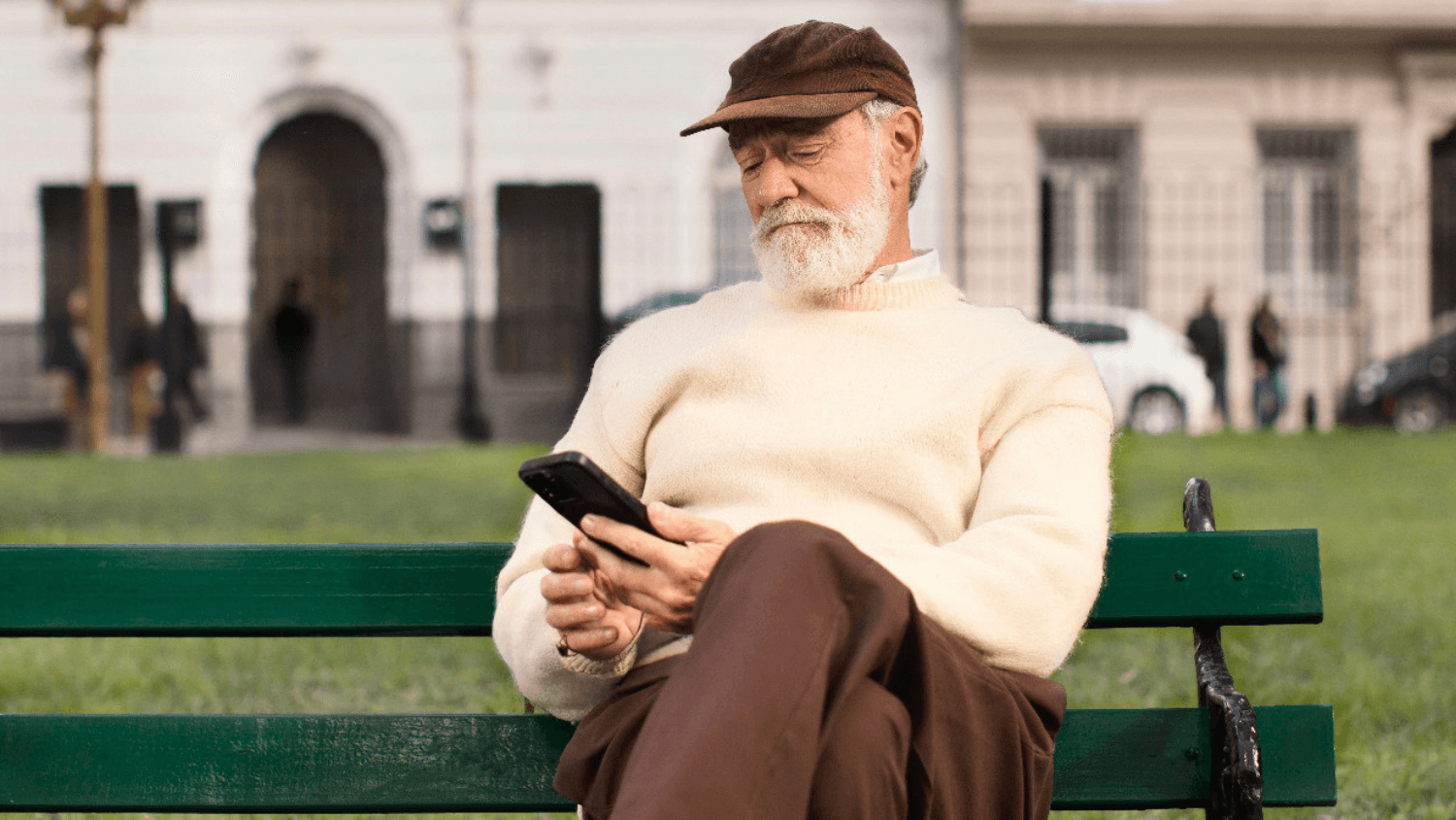 A person sitting on a park bench with a phone in their hands, checking their available credit on their banking app
