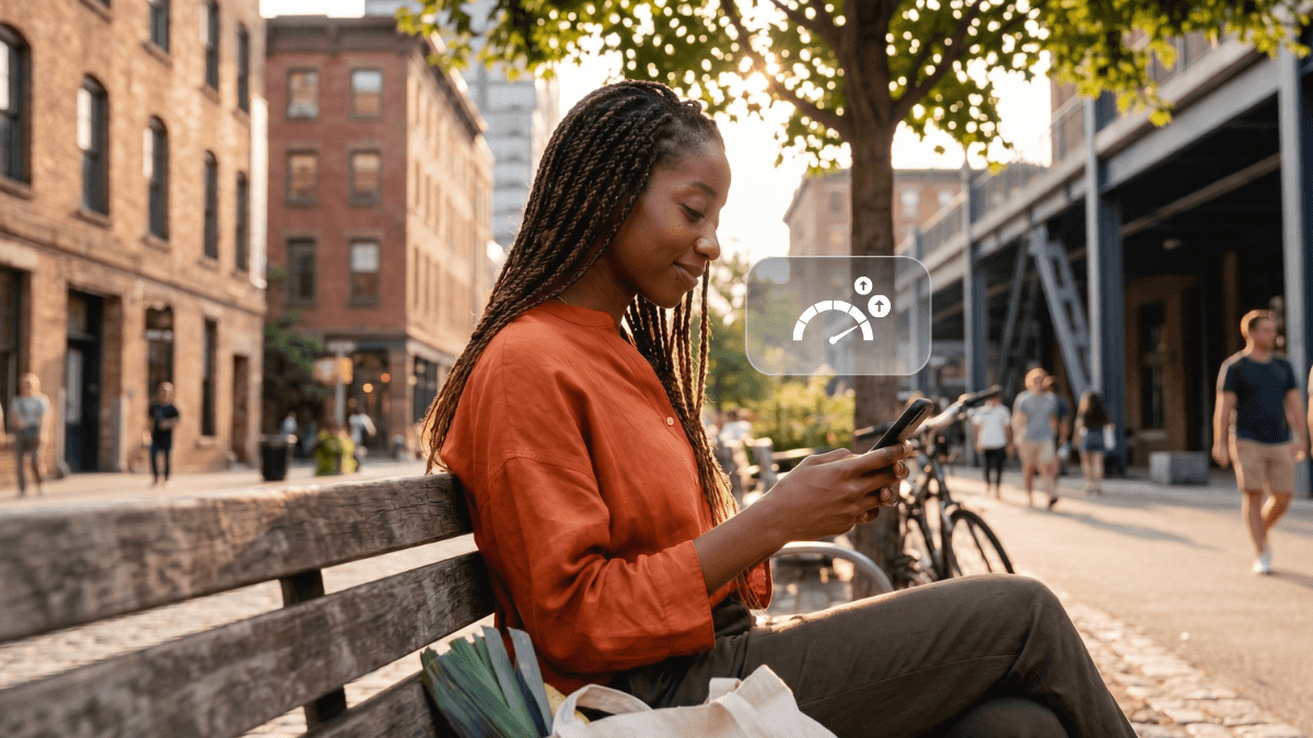 A person sitting on a city bench looking at their phone, featuring a floating digital graphic of an increasing credit dial that highlights how to build credit score in Canada.